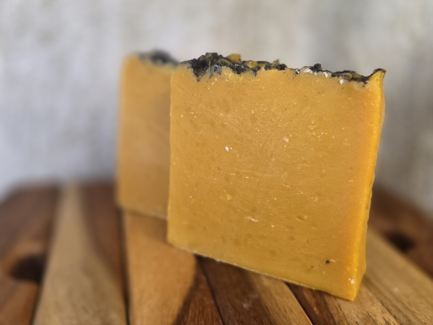 Two saffron-orange soap bars with dark crusted tops, stacked (alternate angle)