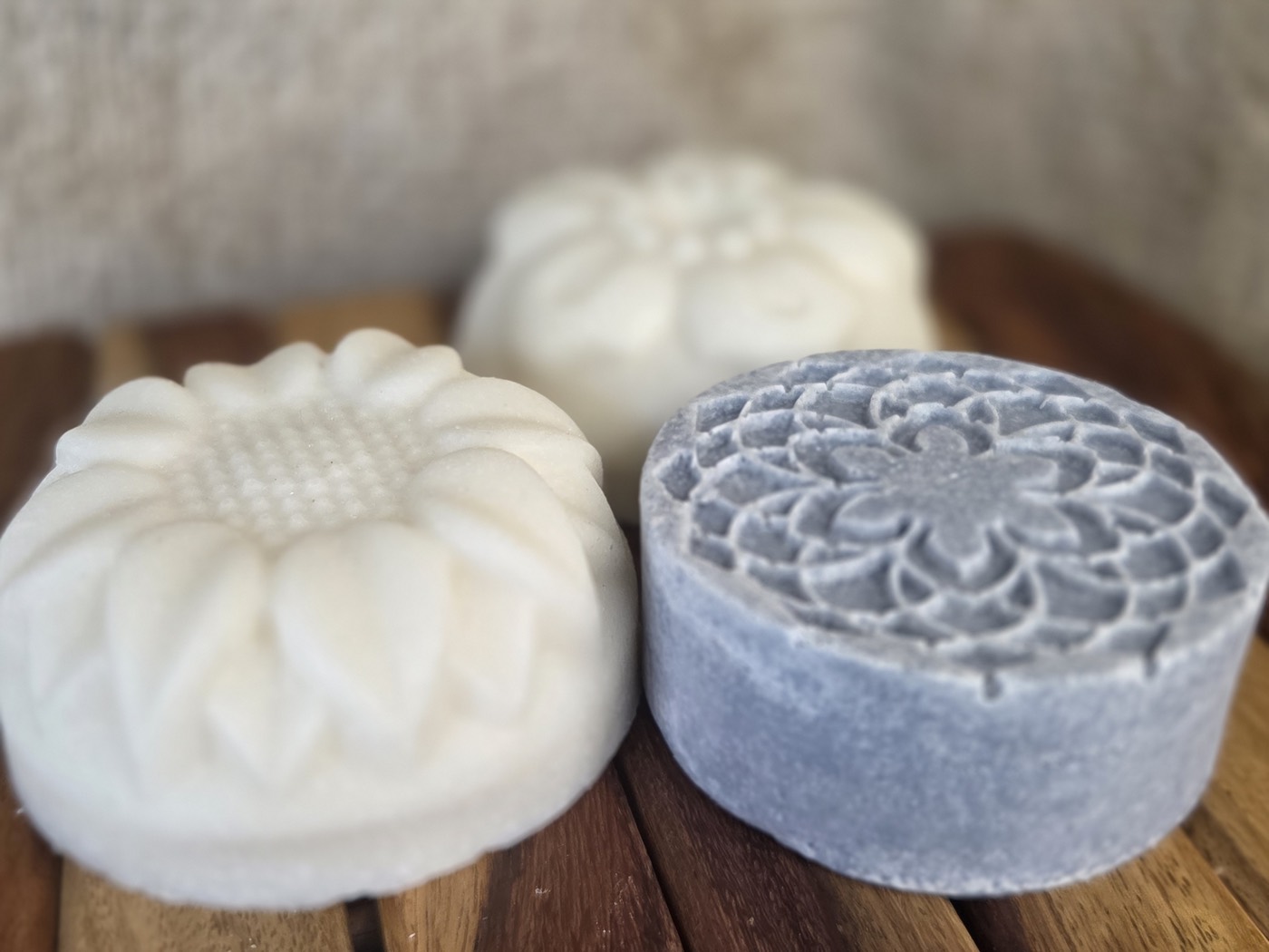 Two white flower-molded salt soap rounds with a blue mandala round behind (alternate angle)